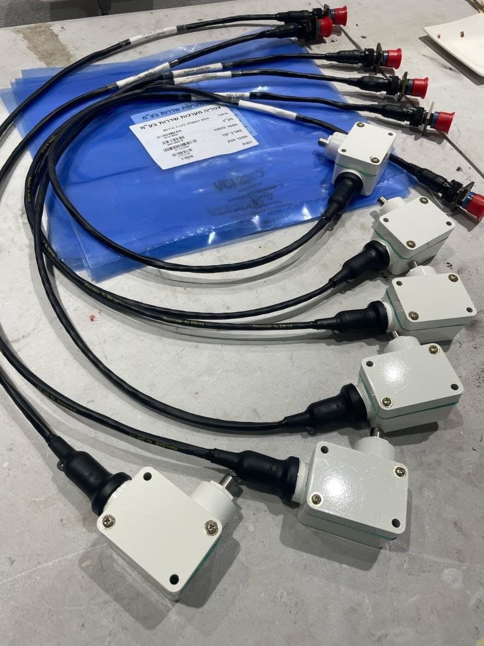 Emergency fuel switch assemblies with white enclosures and black cables ending in red-capped connectors, laid out on a workbench.