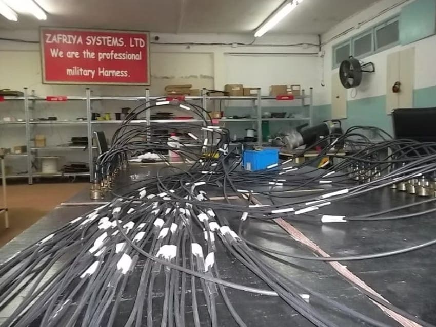A production bench with wiring harnesses and circular connectors being assembled.