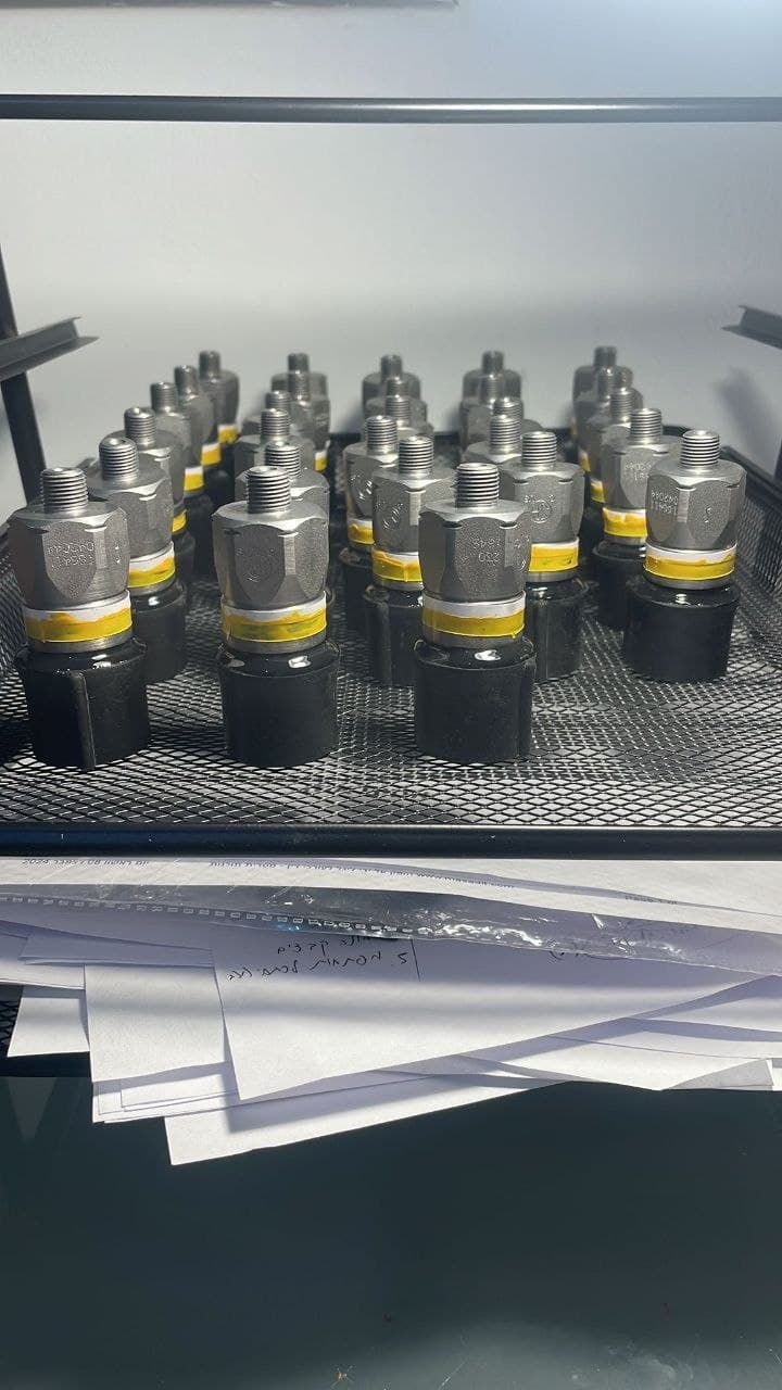 Rows of hydraulic pressure switches with threaded metal fittings, yellow bands and black bases on a mesh shelf.